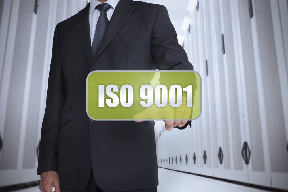 Businessman in a data center selecting a green label with iso 9001 written on it