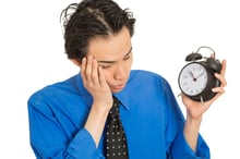 Portrait sleeping young man holding alarm clock isolated on white background. Long working hours, lack of sleep, sleep deprivation, no motivation concept. Face expression