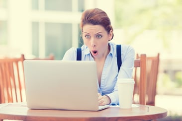Shocked young business woman using laptop looking at computer screen blown away in stupor sitting outside corporate office. Human face expression, emotion, feeling, perception, body language, reaction