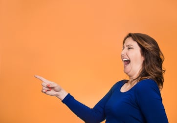 Side view profile portrait middle aged excited happy laughing woman pointing finger at something someone isolated orange background with copy space. Positive human emotion face expression reaction