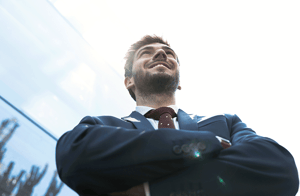 angulo contrapicado de hombre con traje sonriendo con brazos cruzados emprendimiento en latinoamerica