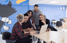 equipo de marketing digital saas sentado alrededor de laptop en mesa