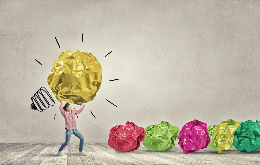 Woman carrying with effort big crumpled ball of paper as creativity sign